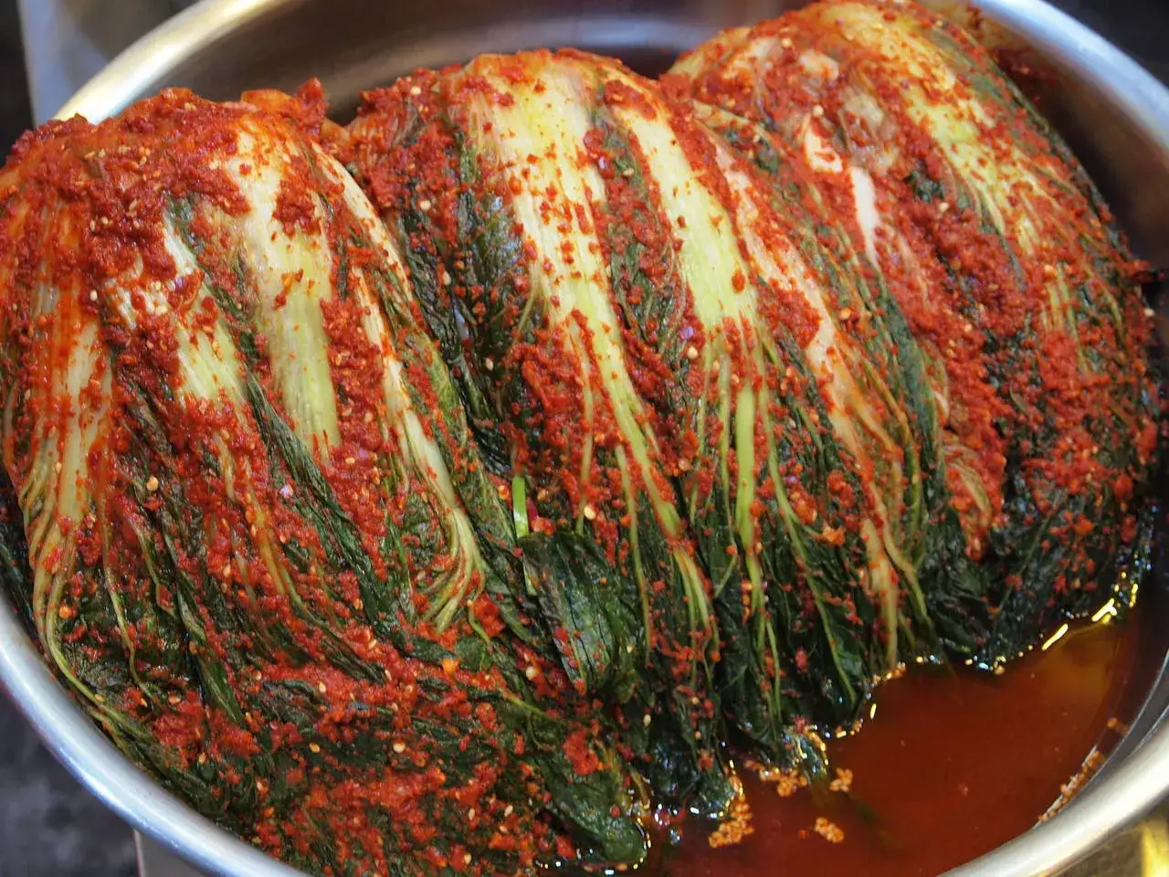 Całe główki kapusty pekińskiej pokryte czerwoną pastą z chili i przyprawami. Tak przygotowuje się tradycyjne, koreańskie kimchi.